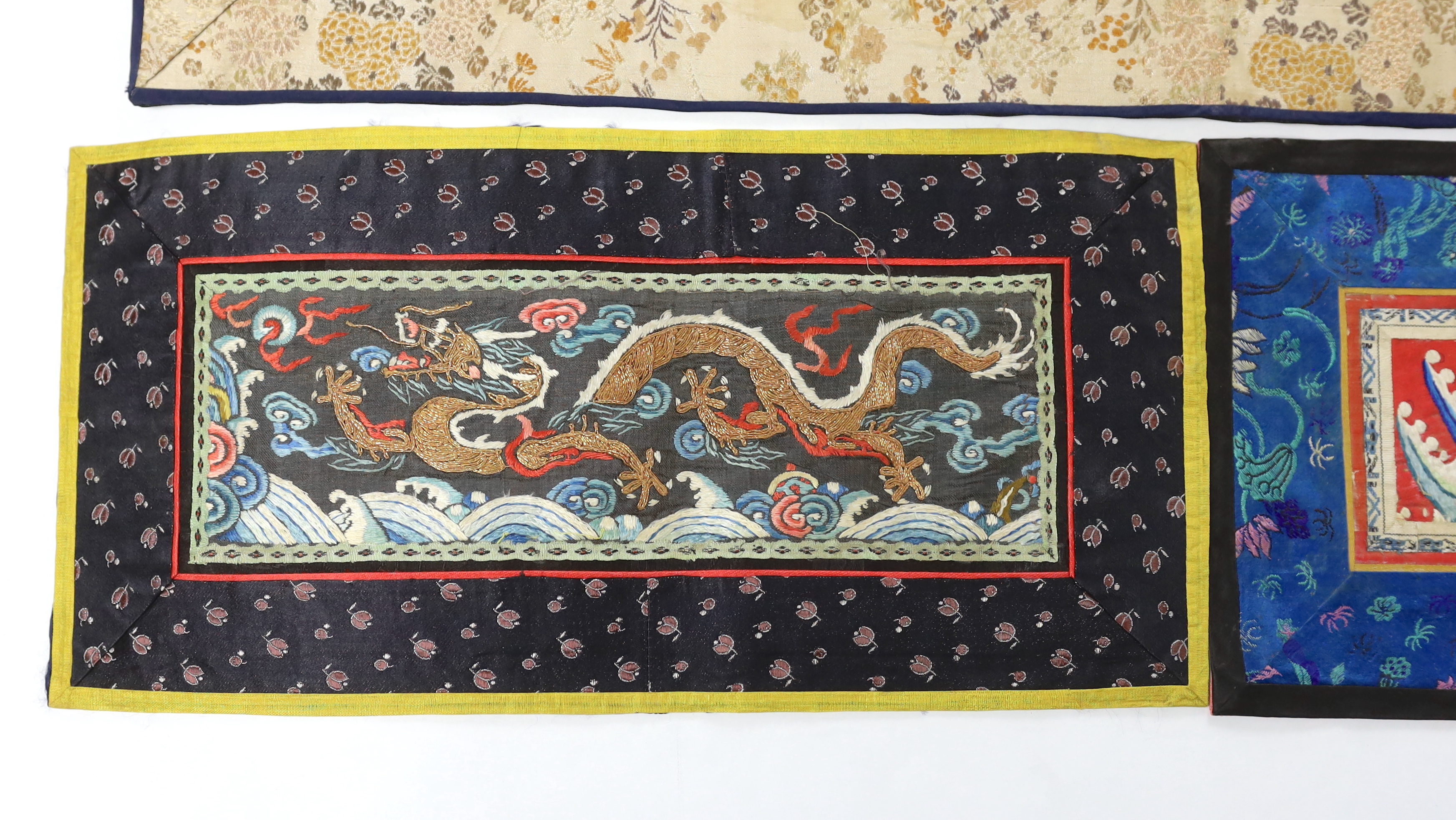 A Chinese late Qing dynasty red silk and polychrome embroidered lishui wave and flaming pearl panel, another smaller metallic dragon panel, an ornate butterfly panel and two other smaller embroidered panels with auspicio